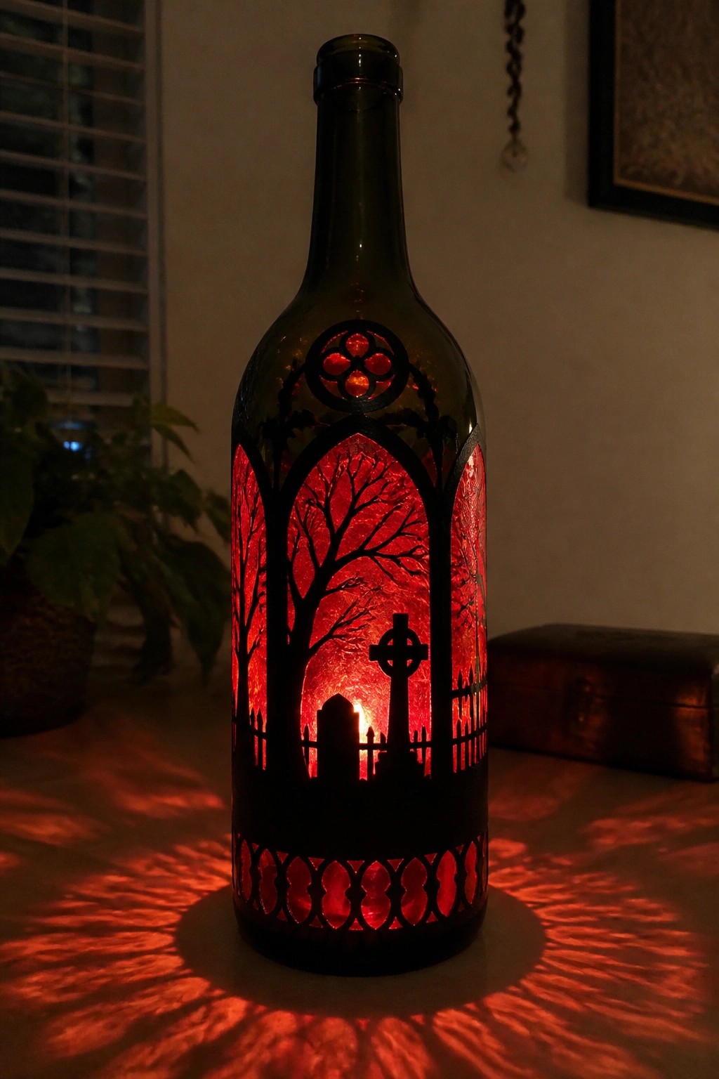 Wine bottle with graveyard cutouts glowing red, casting patterned shadows on table.