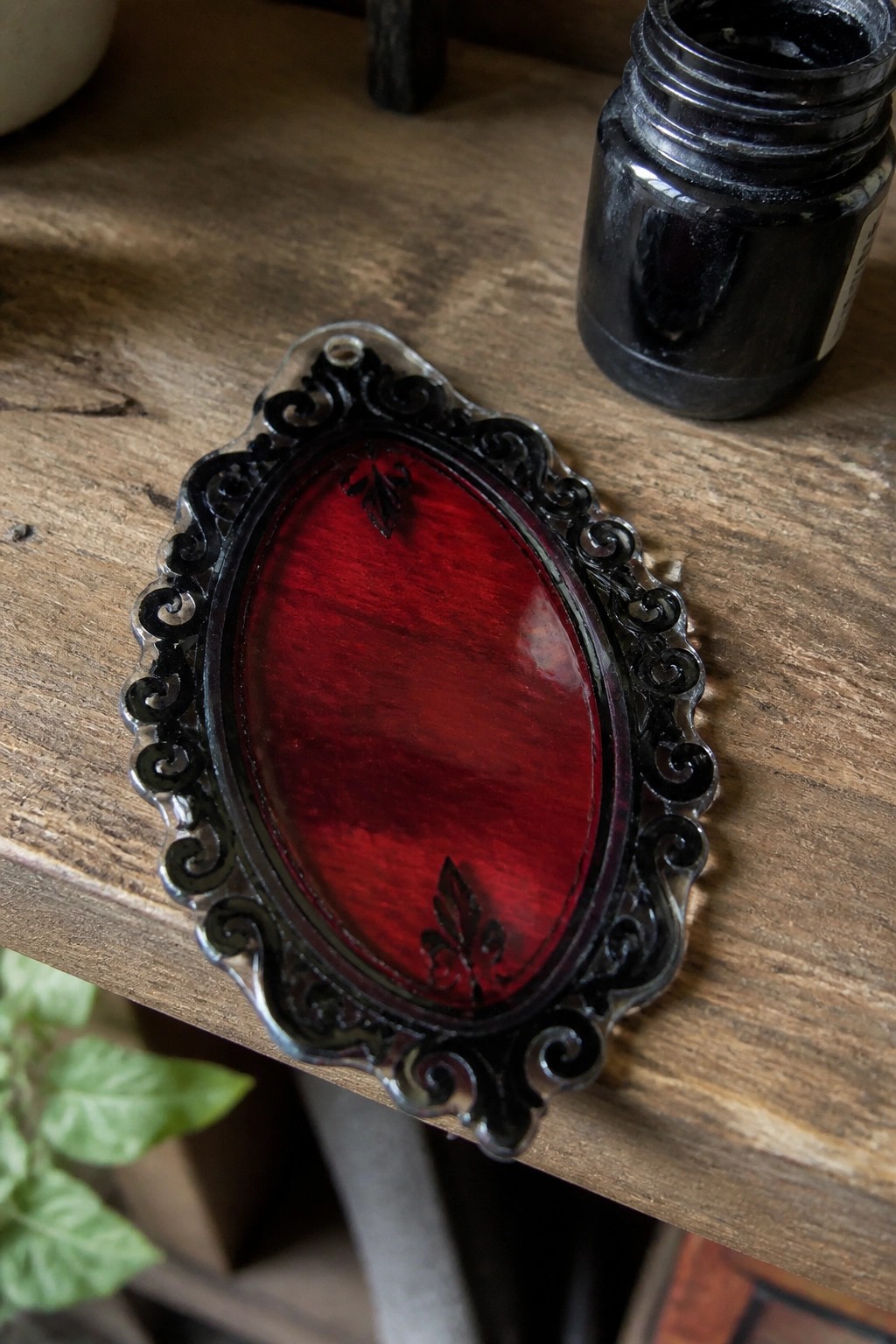 Ornate black scrollwork frame with red translucent oval on wooden table