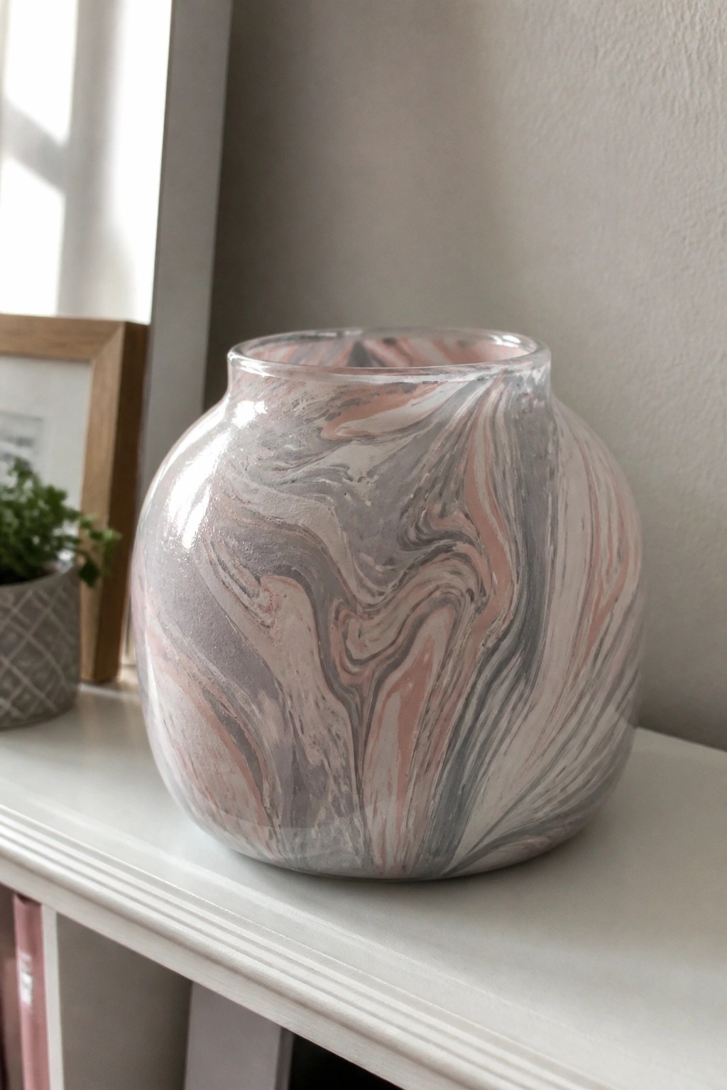 Marbled pink gray and white glass vase on white shelf