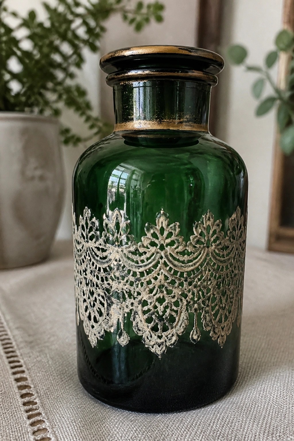 Green glass bottle with intricate metallic lace pattern and gold-trimmed black lid
