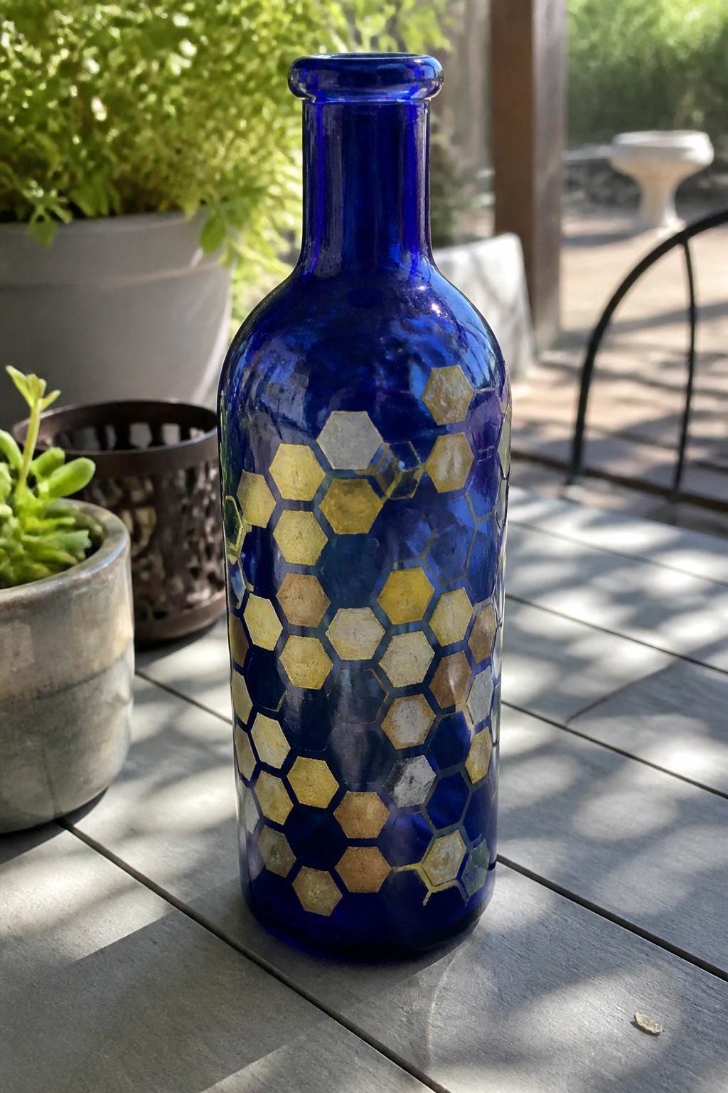 Blue glass bottle with gold and silver honeycomb pattern on wooden table