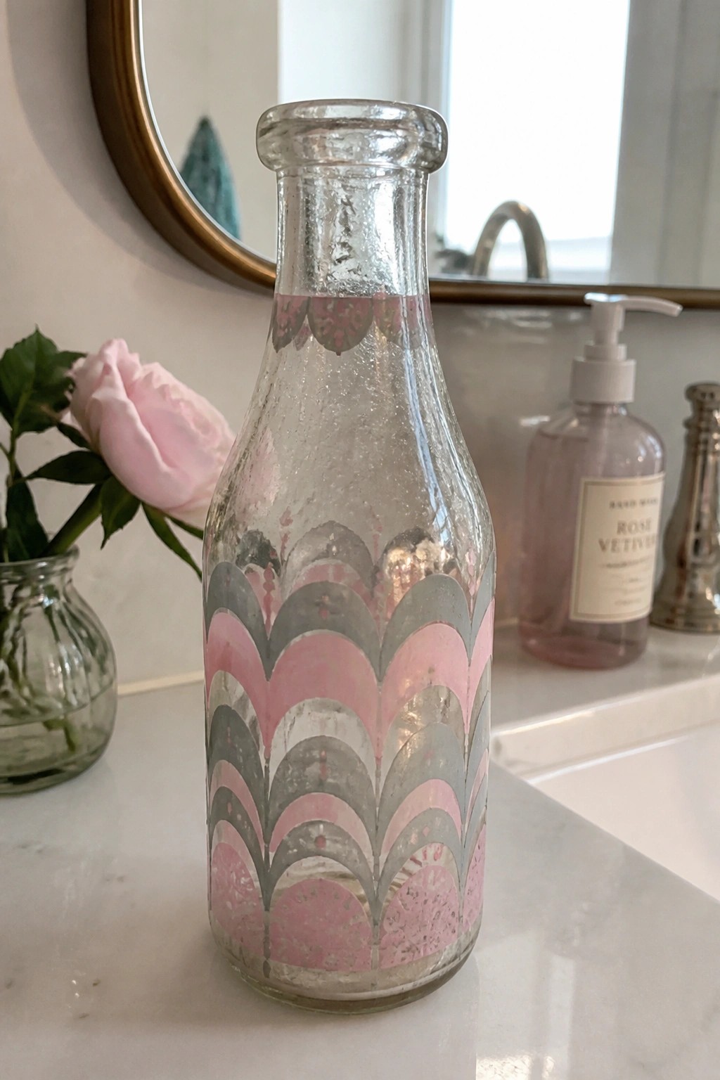 Vintage glass bottle with pink and gray scalloped pattern on marble bathroom counter