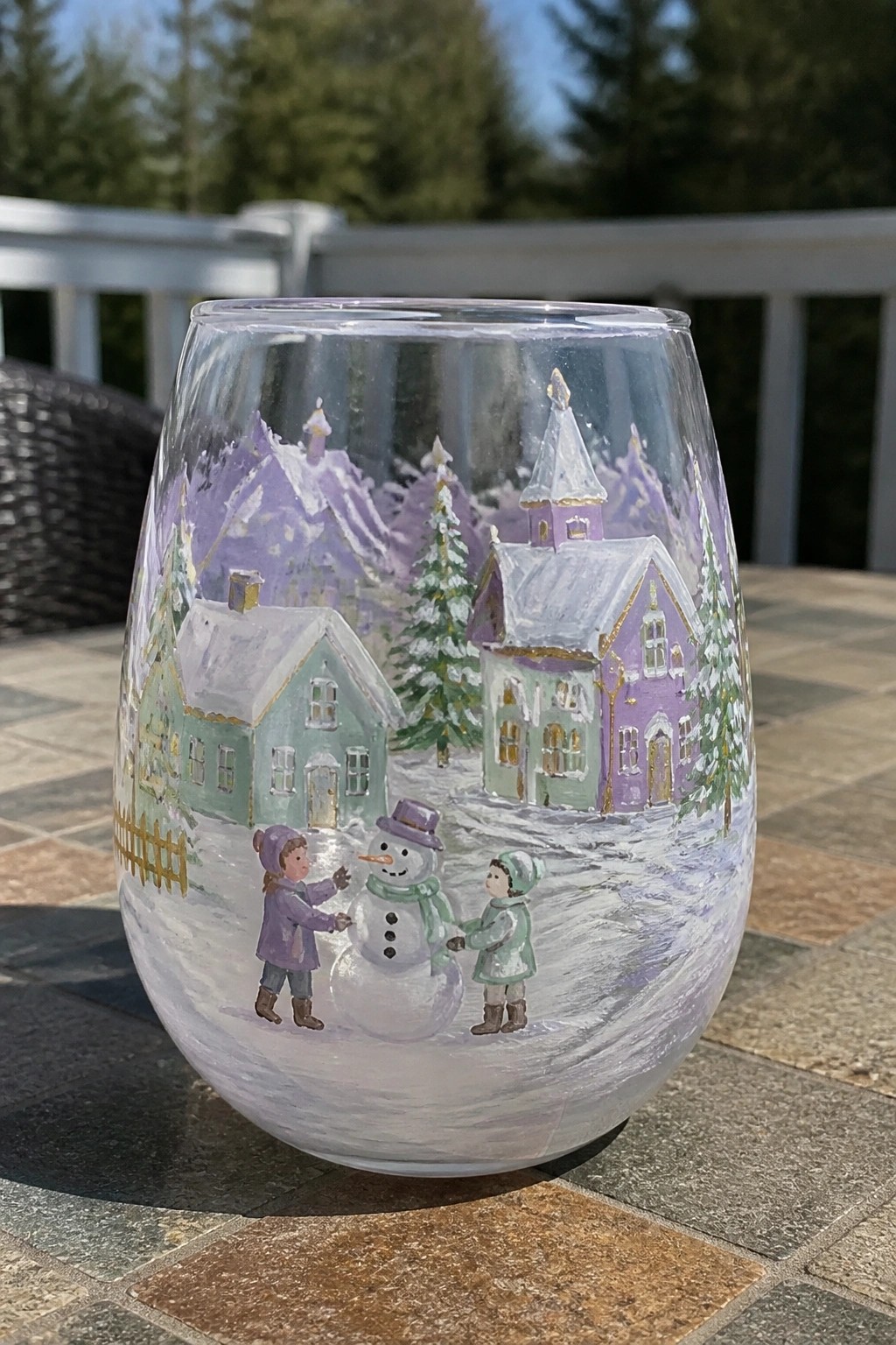 Stemless glass painted with snowy village, snowman, and children in winter coats with gold accents