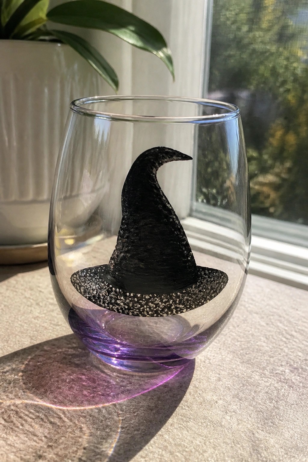 Clear glass with black glitter witch hat and purple base on table