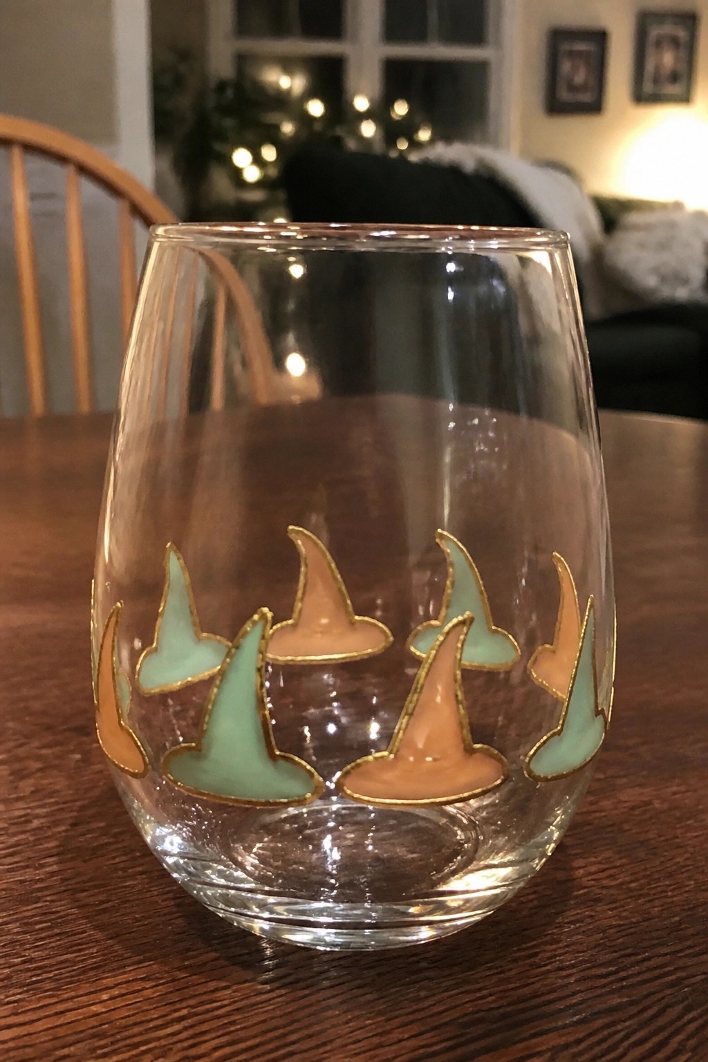 Clear stemless glass with gold-outlined mint green and peach witch hats.
