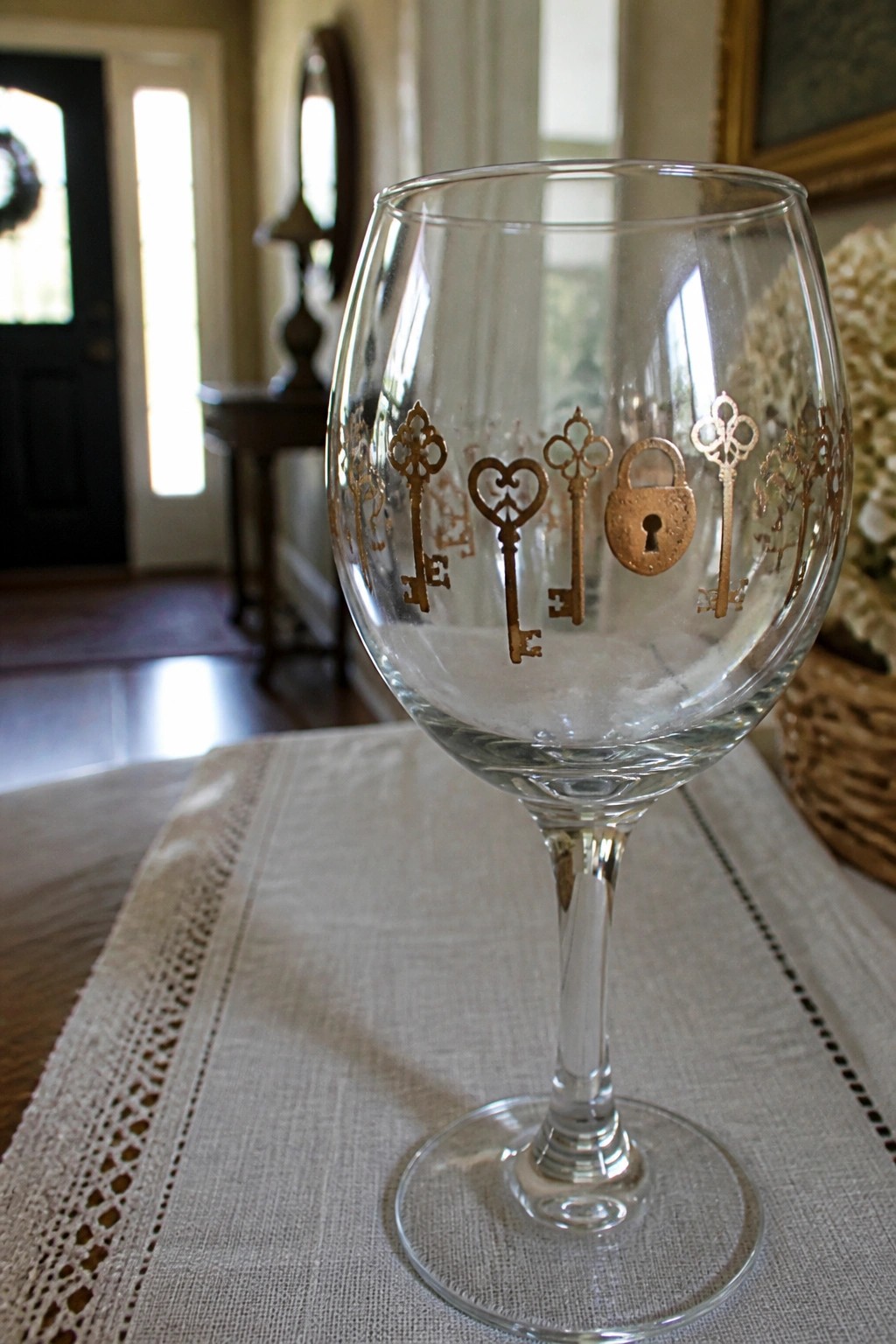 Wine glass with gold key and padlock designs on lace table runner