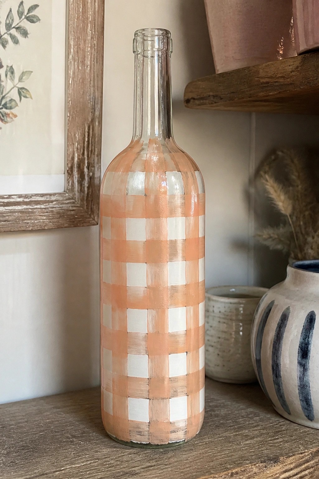 Glass bottle with orange and white checkered paint pattern on wooden surface