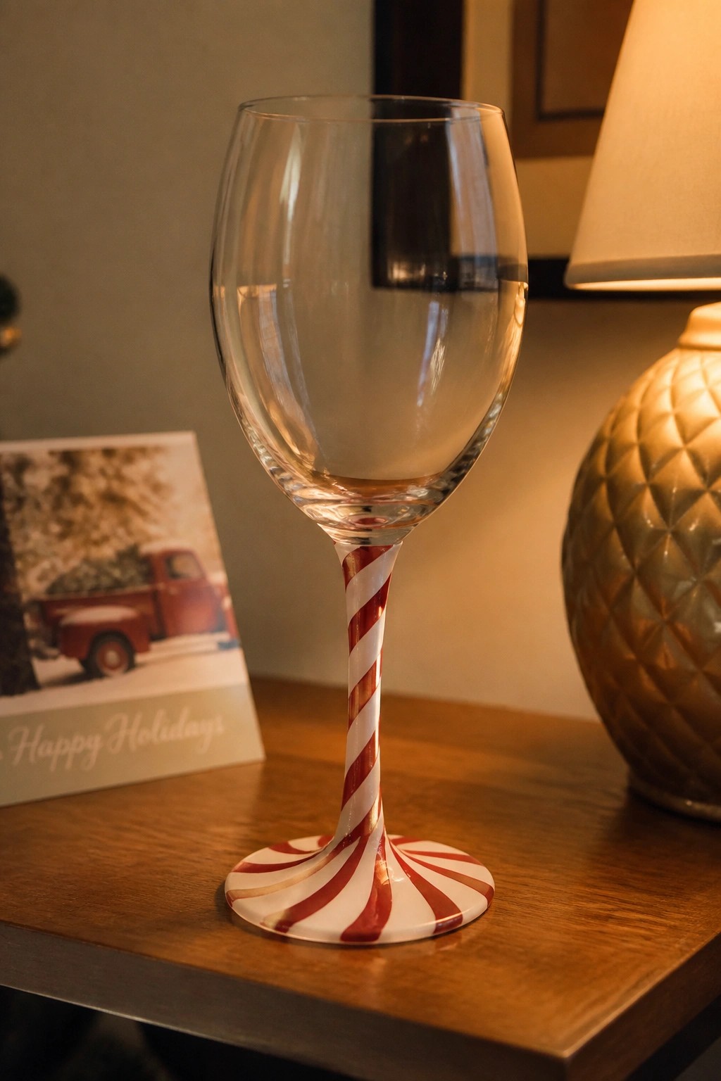 Empty wine glass with red and white candy cane striped stem and base on wood table