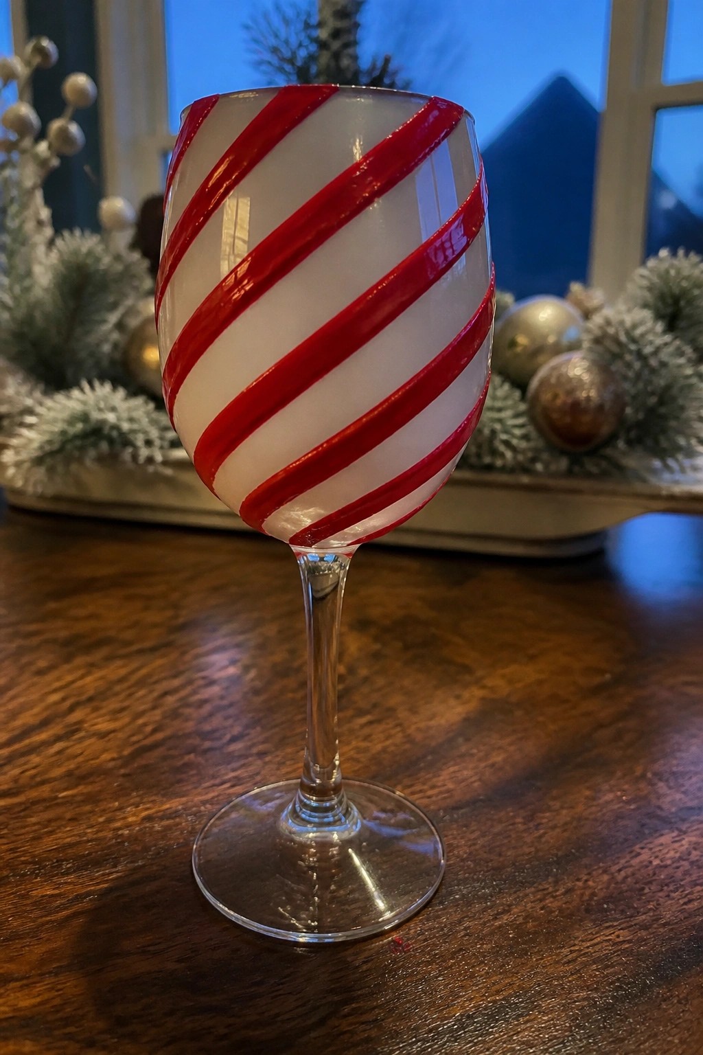 Red-and-white striped wine glass on wooden table with holiday decor