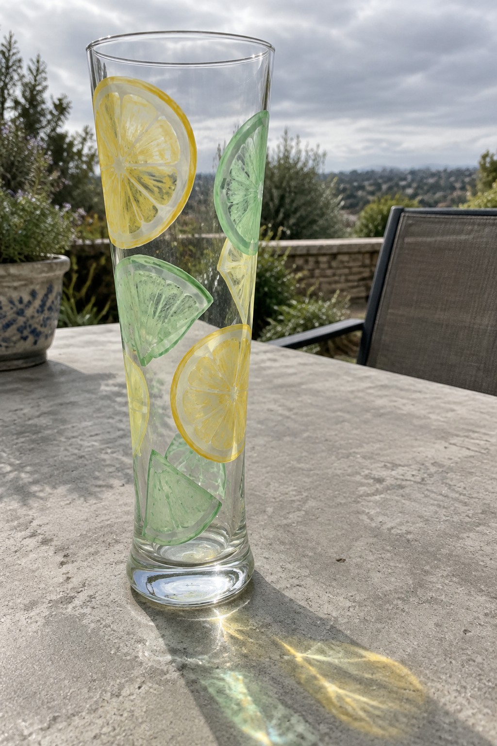 Tall glass with yellow lemon and green lime slices on stone table