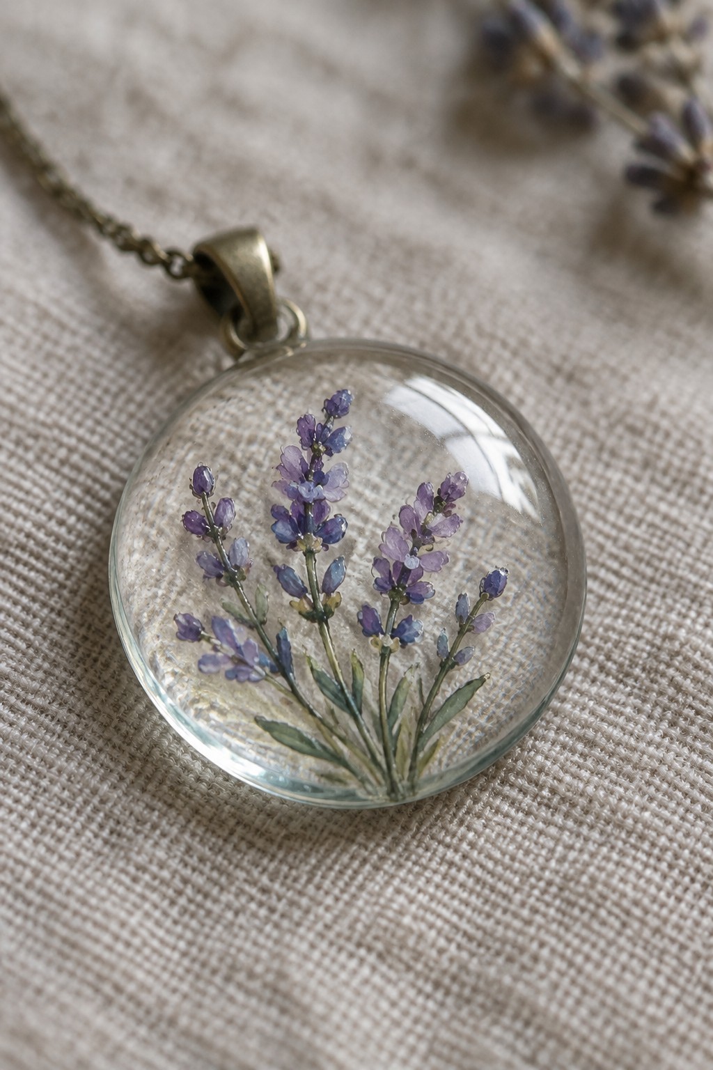 Round glass pendant necklace with purple lavender flowers on beige fabric