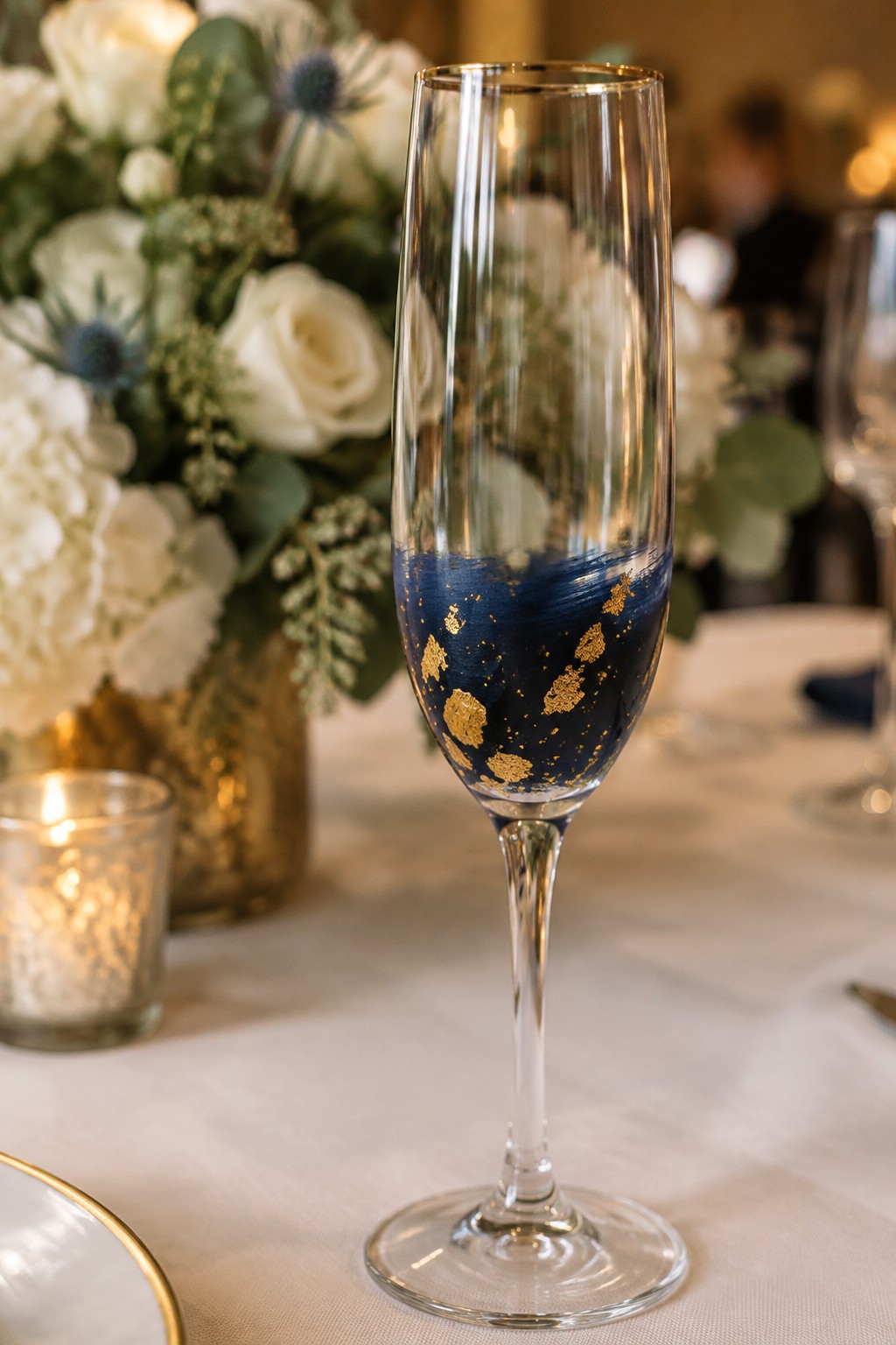 Champagne flute with navy blue brushstrokes and gold leaf accents on table