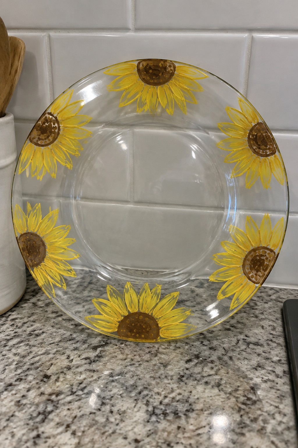 Clear glass plate with yellow sunflowers on granite countertop by white tiles