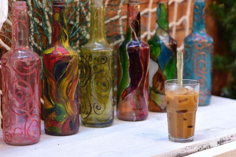 Six upright hand-painted glass bottles arranged on a weathered wooden table